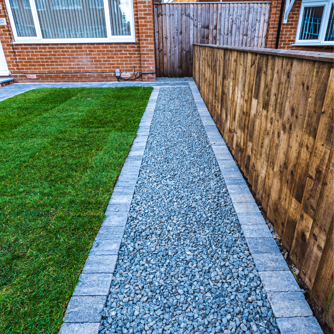 Fresh lawn beside gravel path and timber fencing